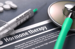 lose-up of a syringe, stethoscope, and pills on a document labeled "Hormone therapy."