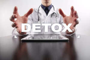 Doctor with hands outstretched over a tablet, with the word DETOX displayed.