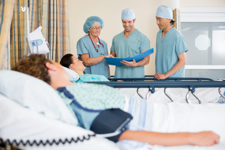 Man lying in bed with doctors in the background.