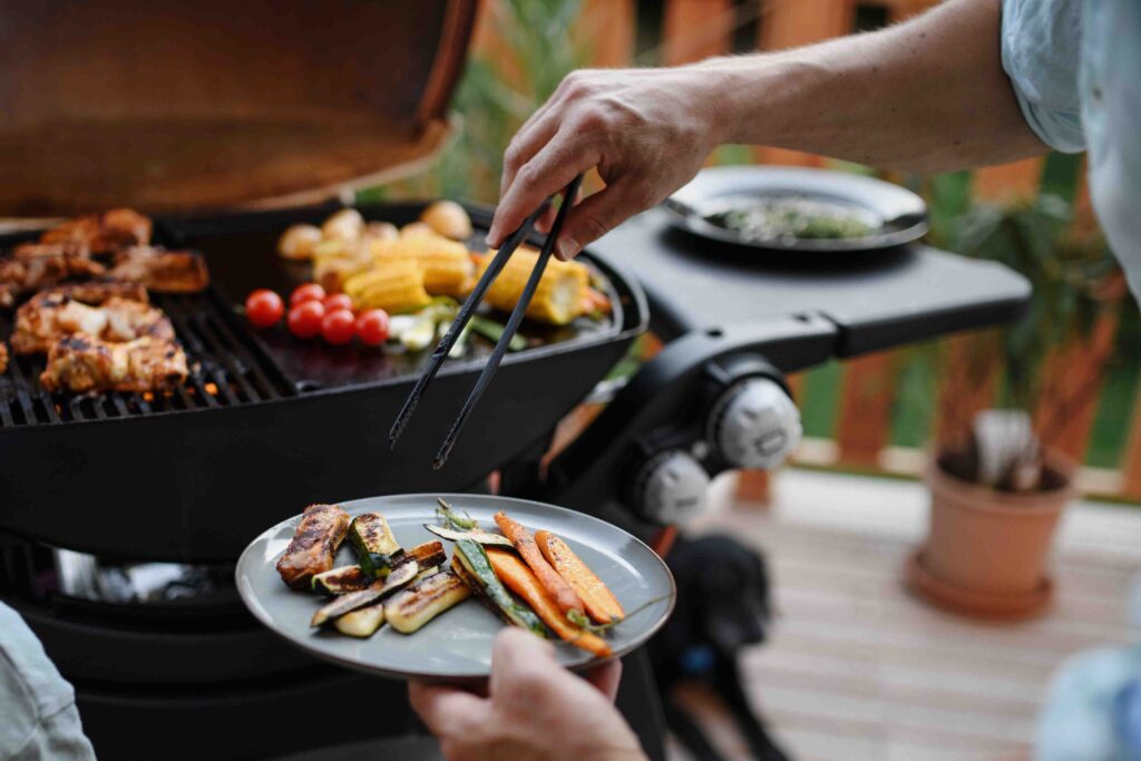 Man barbecuing vegetables on a grill.
