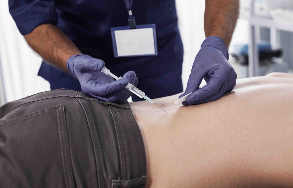 Doctor performing muscle injection on patient's back.