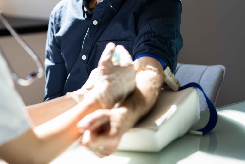 Medical practitioner taking blood from patient.