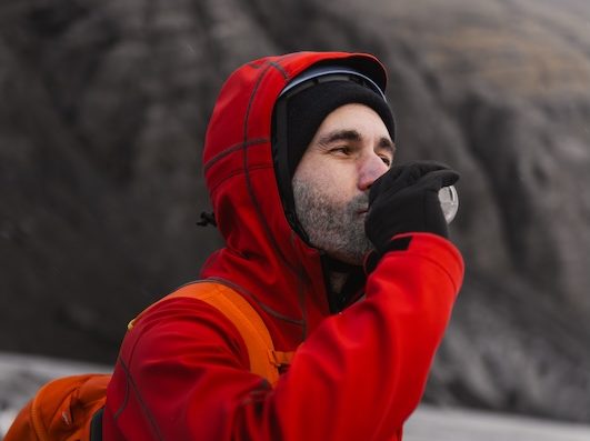 Male,Hiker,Wearing,Red,Jacket,And,Backpack,Drinking,Water,From Max Hydration IV therapy option. Hiker drinking water.