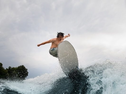 Beautiful,View,On,Splashing,Wave,And,Sportive,Man,Skilfully,Jumping Wellness Wave IV therapy option. Man surfing.